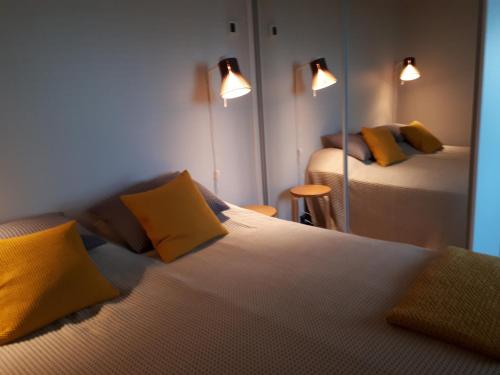 a bedroom with two beds with yellow pillows and a mirror at Graniitti in Hanko