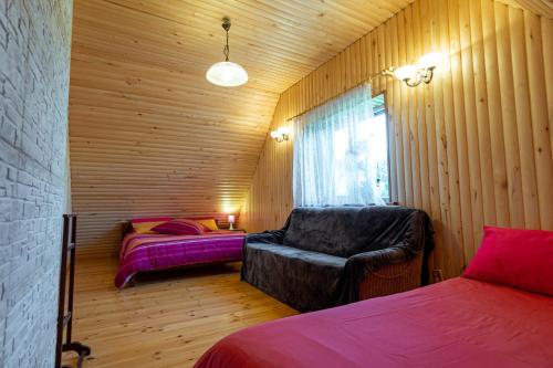 a bedroom with a couch and a bed and a window at Sodyba "Baltalaukis" in Didžiosios Kabiškės