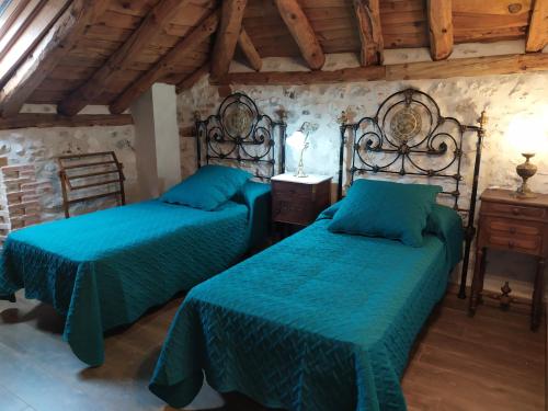 a bedroom with two beds with green comforter at Casa Rural Las Cotarras in Sanchonuño