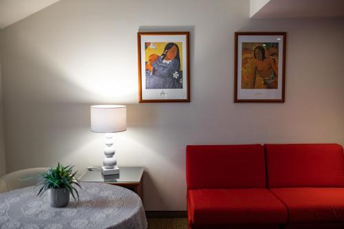 a living room with a red couch and two pictures at Hotel Crystal in Preganziol