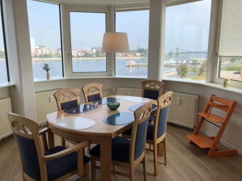 a dining room with a table and chairs and windows at Apartment 113 in Wilhelmshaven