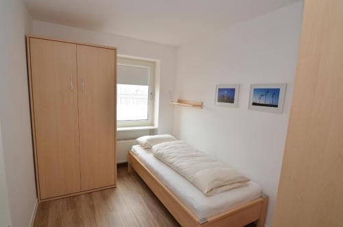 a bedroom with a bed and a cabinet and a window at Apartment 113 in Wilhelmshaven