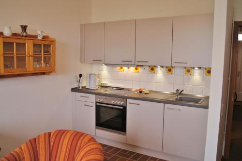 una cocina con armarios blancos y fregadero en An der Allee 20 A, en Dahme
