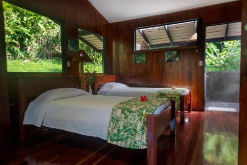 a bedroom with two beds and two windows at Tiskita Jungle Lodge in Pavones