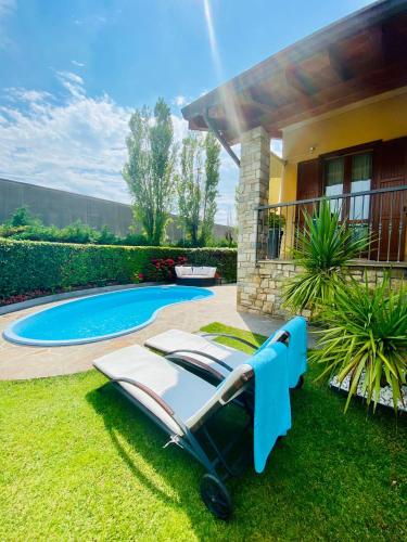 a lounge chair in the grass next to a swimming pool at Franciacorta Suite in Corte Franca