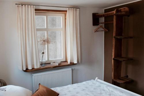Un dormitorio con una ventana con cortinas blancas y una cama en Landhaus Weserbergland - Anton, en Vahlbruch