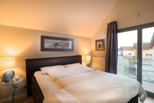 ハイリゲンハーフェンにあるOstsee - Appartement Nr 63 "Möwennest" im Strand Resortのベッドルーム1室(ベッド1台、大きな窓付)