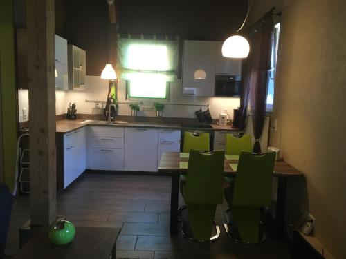 a kitchen with a table and green chairs at LandLoft in Tauberbischofsheim
