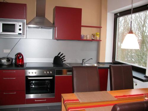 una cucina con armadi rossi, piano cottura e tavolo di Ferienwohnung Oelstorf a Eckernförde