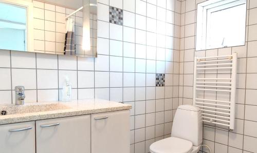 a white bathroom with a toilet and a sink at Fiskerhuset i Øster Hurup - i byen, ved stranden in Øster Hurup