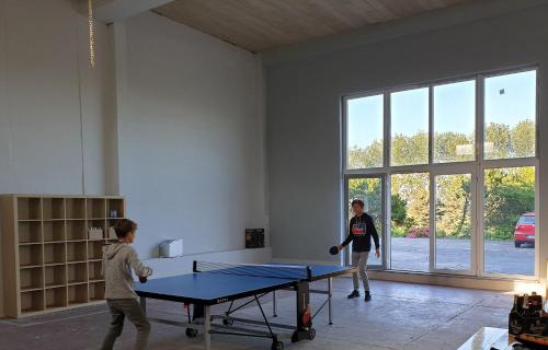 zwei Kinder spielen Tischtennis in einem Zimmer mit einer Tischtennisplatte in der Unterkunft Quaduxenbarg in Hornstorf