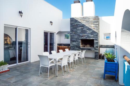 un comedor con una mesa y sillas blancas y una chimenea en Bellamente Sirene, en Gansbaai