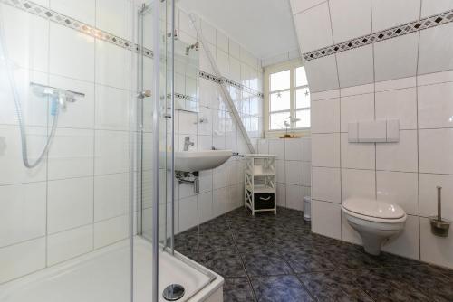 uma casa de banho branca com um lavatório e um WC em Muschelsucher em Wrixum