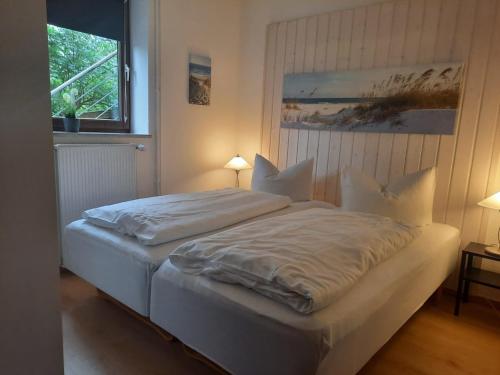- une chambre avec un lit doté de draps blancs et une fenêtre dans l'établissement Nielsen Apartment 1, à Hüsby