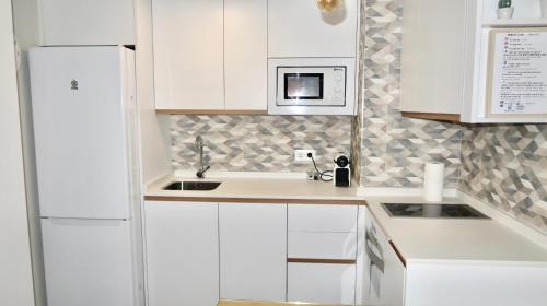 a white kitchen with a sink and a microwave at Sevilla Alameda PG Apartamentos in Seville