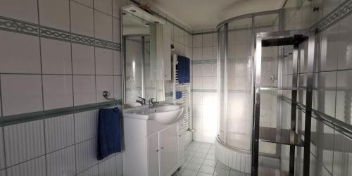 uma casa de banho branca com um lavatório e um chuveiro em Achtern em Heringsdorf