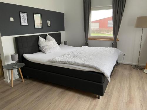 1 dormitorio con 1 cama con sábanas blancas y ventana en Moderne Ferienwohnung im skandinavischen Stil KK en Heide