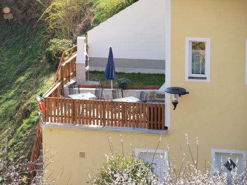 a deck with chairs and an umbrella on the side of a house at Weinbau Weidenauer in Wösendorf