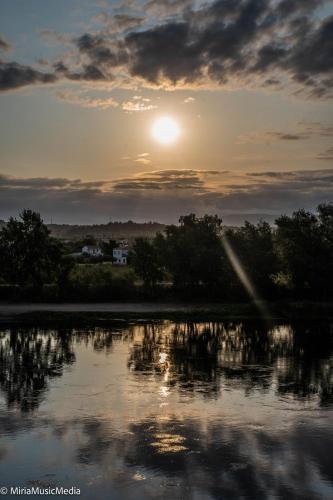 a sunset over a body of water with trees at River Ebro Apartments in Móra d'Ebre