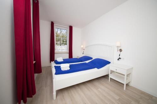 a bedroom with a bed with blue sheets and a window at Schleiblick App 8 in Rabenkirchen-Faulück