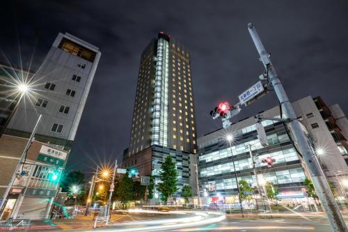 a city street at night with tall buildings at Hundred Stay Tokyo Shinjuku in Tokyo