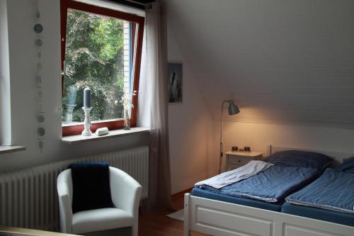 um quarto com uma cama, uma cadeira e uma janela em Ferienwohnung weißes Haus em Meeschendorf