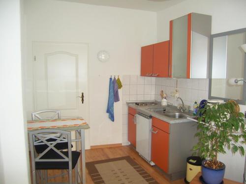 eine Küche mit orangefarbenen und weißen Schränken und einem Waschbecken in der Unterkunft Parterrewohnung in Wismar