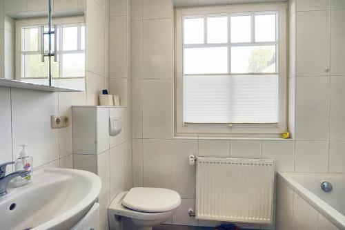 a white bathroom with a toilet and a sink at Cubes Insel in Zingst