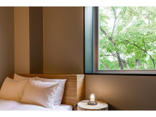 a bedroom with a bed and a window with a tree at HOTEL KARUIZAWA CROSS - Vacation STAY 56455v in Karuizawa