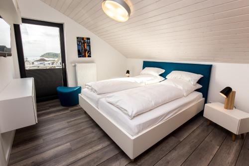 a bedroom with a large white bed with a blue headboard at Kyst 3 in Neustadt in Holstein