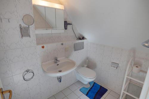 uma casa de banho branca com um WC e um lavatório em Strandlust - Whg 14 em Zingst