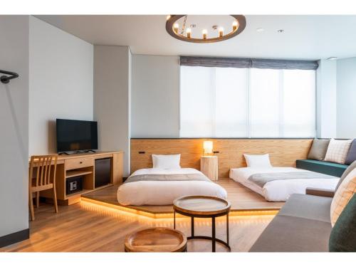 two beds in a room with a couch and a tv at HOTEL KARUIZAWA CROSS - Vacation STAY 56435v in Karuizawa