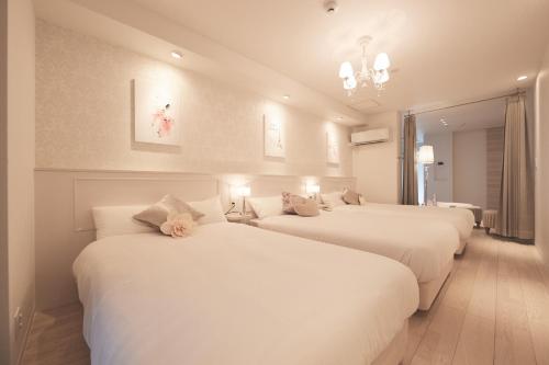 松戸市にあるReLA Higashimatsudo - Vacation STAY 66996vの白いシーツとシャンデリアが備わるベッド3台が備わる客室です。