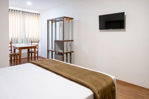 a bedroom with a bed and a tv on a wall at Bliss Hotel Vale do Café in Vassouras