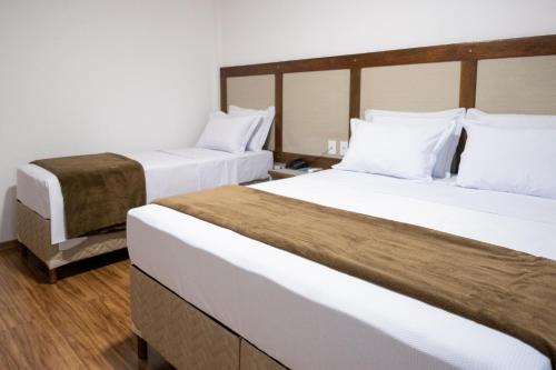 two beds in a hotel room with white sheets at Bliss Hotel Vale do Café in Vassouras