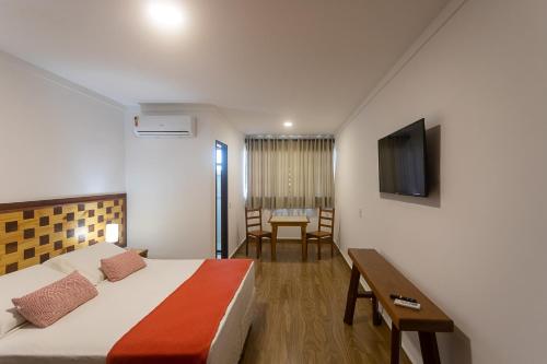 a bedroom with a bed and a desk and a television at Bliss Hotel Vale do Café in Vassouras