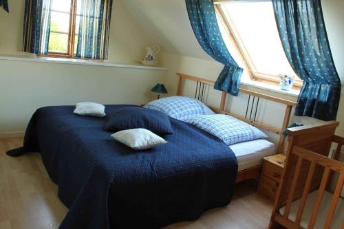 a bedroom with a blue bed with pillows and a window at Haus Wildgans - Ferienwohnung Sonnenblume in Behrensdorf