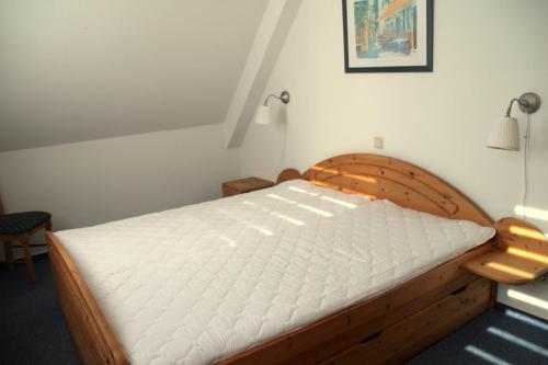 a bedroom with a wooden bed with white sheets at Boddenwelle in Zingst