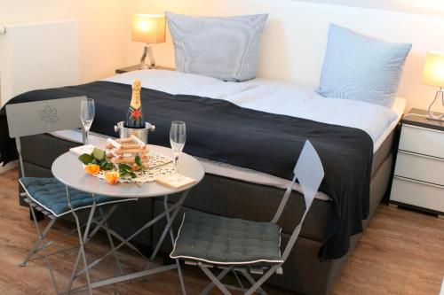 ハイリゲンハーフェンにあるOstsee - Appartement Nr 97 "Albatros" im Strand Resortのベッド1台(テーブル、椅子2脚、ワイングラス付)