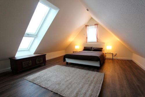um quarto no sótão com uma cama e 2 janelas em Herrmannshof Haby App 3 Kiek ut em Haby