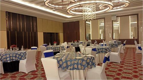 a banquet hall with tables and white chairs and a chandelier at Welcomhotel By ITC Hotels, Katra in Katra
