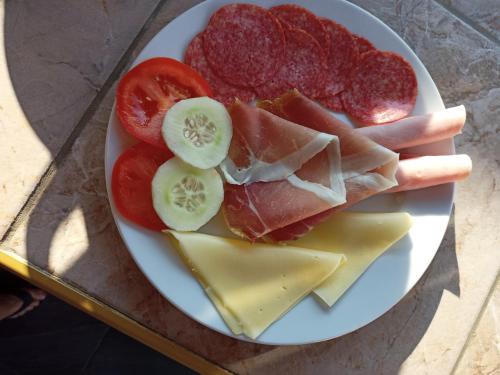 a plate of food with meat cheese and tomatoes at Apartments Ruža Dragove Dugi otok in Dragove