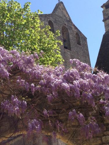 a church with purple flowers on a wall at L'Esplanade in Domme