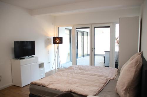 a white bedroom with a bed and a television at Casa Kronengarten Nr 5 in Hilden