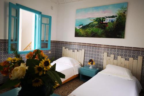 a bedroom with two beds and a vase of flowers at Dar Evelyne in Mahdia