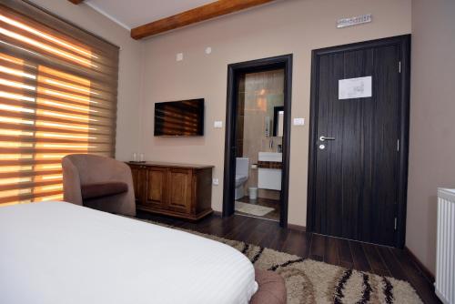 a bedroom with a bed and a desk and a door at Garni Hotel Kaća in Kragujevac