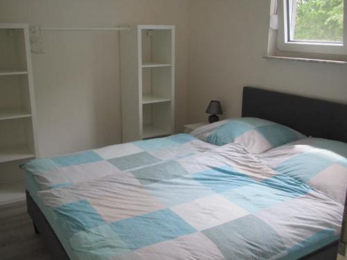 ein Schlafzimmer mit einem Bett mit einer blauen und weißen Decke in der Unterkunft Barons Ferienappartement C in Dargun