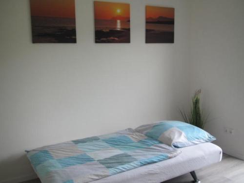 Bett in einem Zimmer mit drei Bildern an der Wand in der Unterkunft Barons Ferienappartement C in Dargun