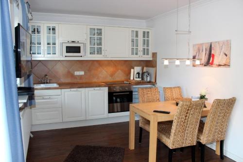 ハイリゲンハーフェンにあるLANDHAUS AM HAFEN im EGの白いキャビネット、木製テーブルと椅子付きのキッチンが備わります。