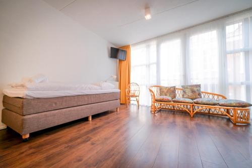 a bedroom with a bed and a couch and windows at Pink Flamingo Boutique Hostel in The Hague